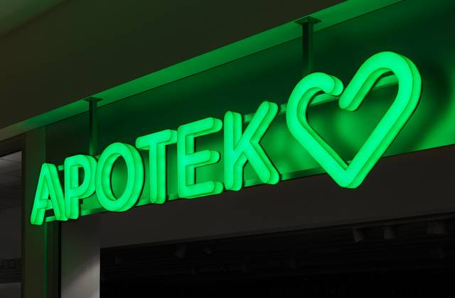 A vibrant green neon sign that reads 'APOTEK' next to a heart-shaped symbol, glowing against a dark